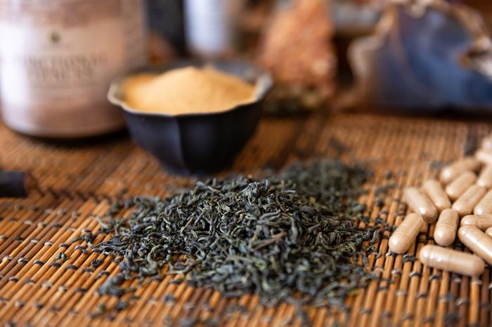 Raw botanical ingredients: tea leaves, root powder, and capsules